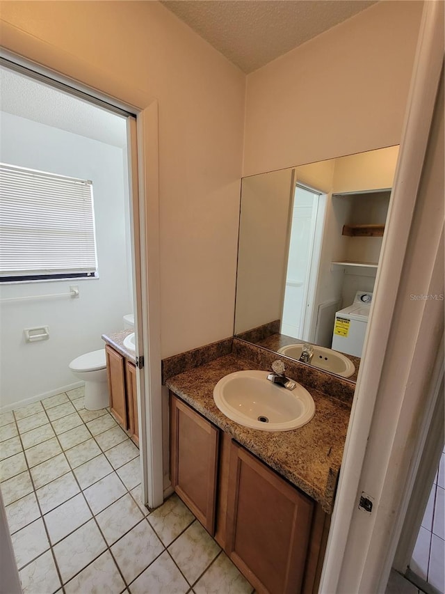 bathroom with tile patterned flooring, washer / dryer, vanity, and toilet