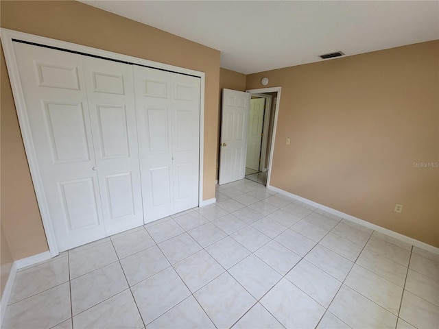 unfurnished bedroom with light tile patterned flooring and a closet