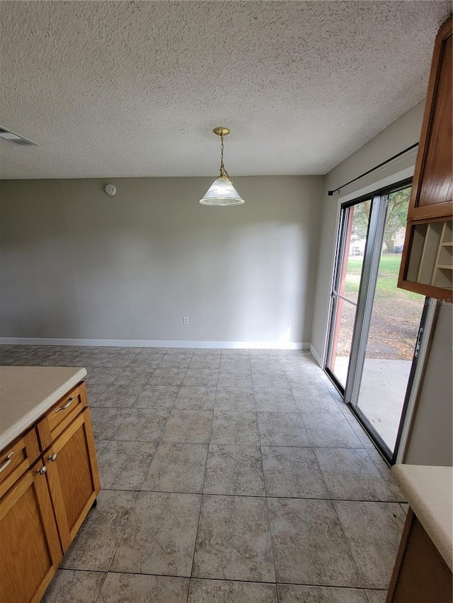 unfurnished dining area featuring a textured ceiling