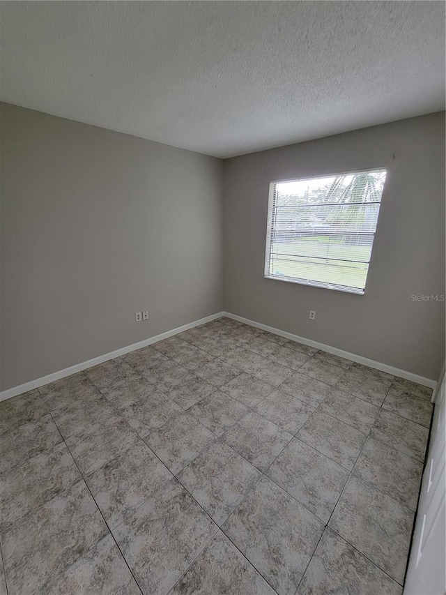 tiled spare room with a textured ceiling