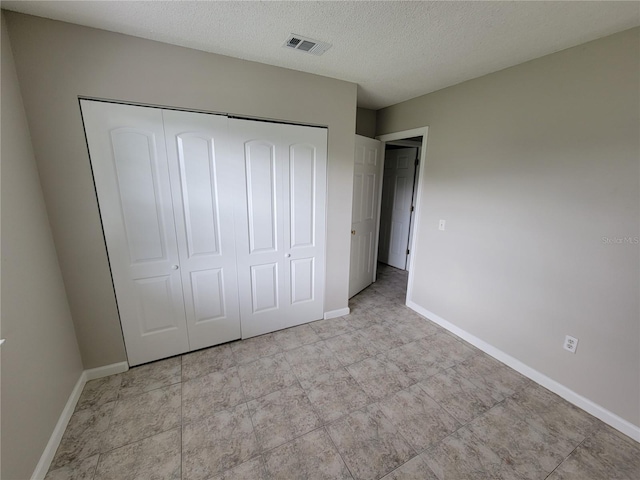 unfurnished bedroom with a textured ceiling and a closet