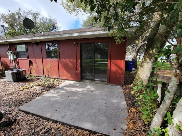 view of exterior entry featuring a patio and central AC unit