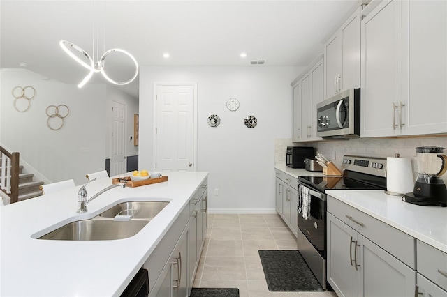 kitchen with appliances with stainless steel finishes, tasteful backsplash, sink, light tile patterned floors, and hanging light fixtures