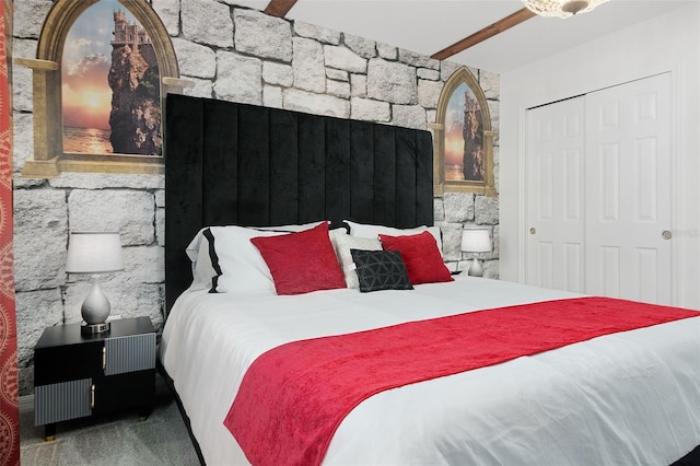 bedroom featuring beam ceiling, carpet floors, and a closet