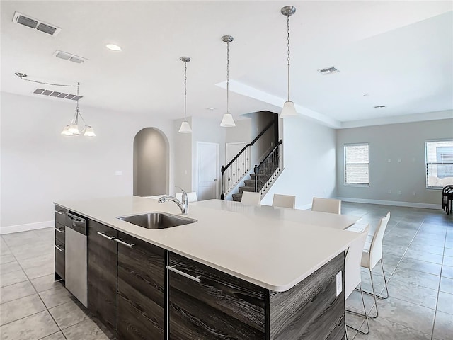 kitchen featuring sink, decorative light fixtures, stainless steel dishwasher, light tile patterned floors, and a large island