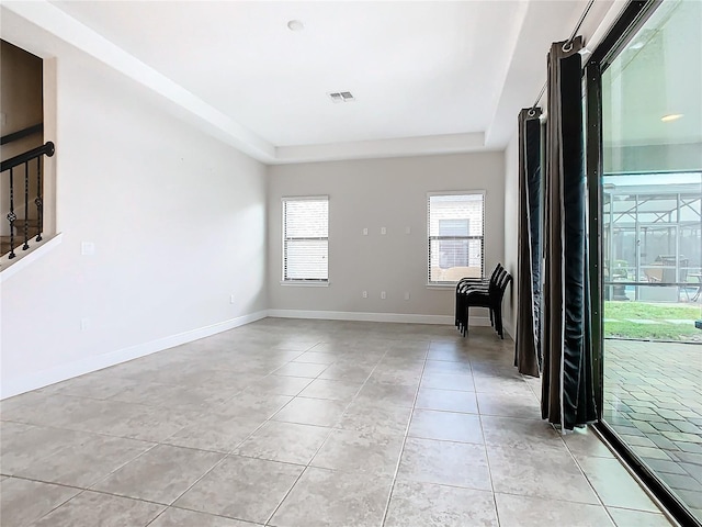 foyer entrance with light tile patterned floors and a tray ceiling