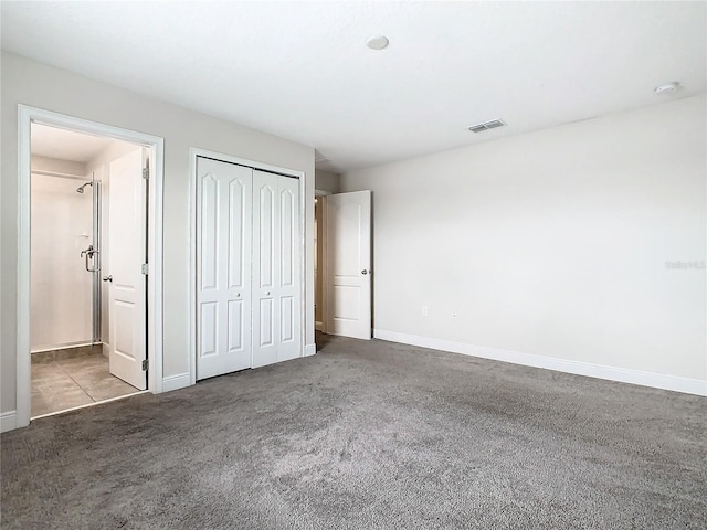 unfurnished bedroom with dark colored carpet and a closet