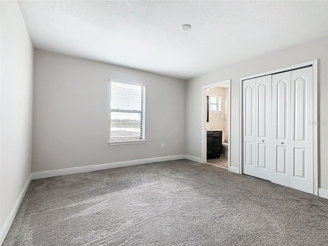 unfurnished bedroom with carpet flooring, connected bathroom, and a closet