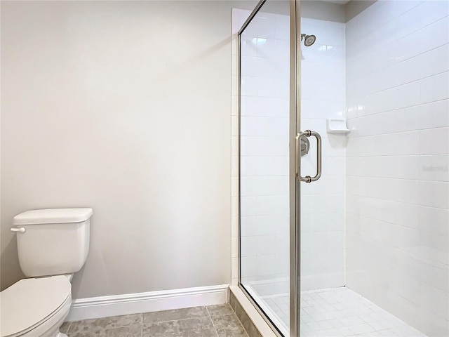 bathroom featuring tile patterned floors, toilet, and a shower with door