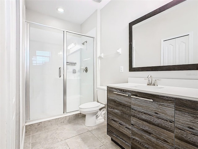 bathroom featuring tile patterned floors, vanity, a shower with shower door, and toilet