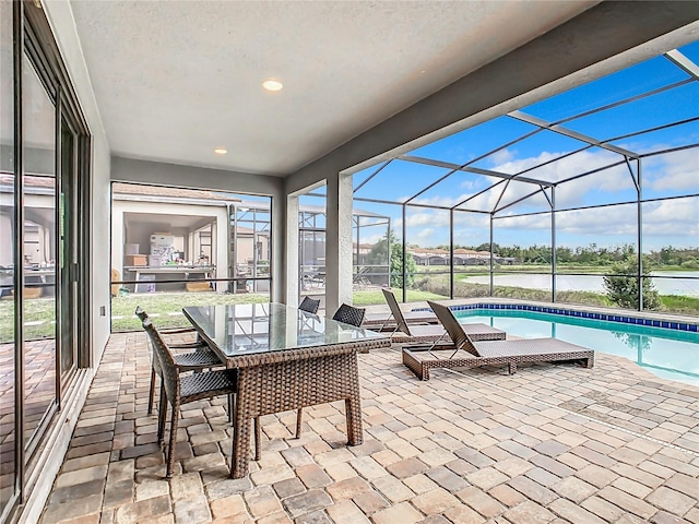 view of patio featuring glass enclosure and a water view