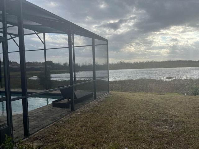 exterior space featuring a yard, a water view, and glass enclosure