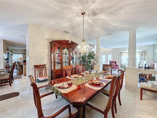 carpeted dining room featuring decorative columns and an inviting chandelier