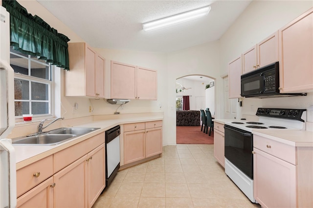 kitchen featuring lofted ceiling, white appliances, sink, light tile patterned floors, and a textured ceiling