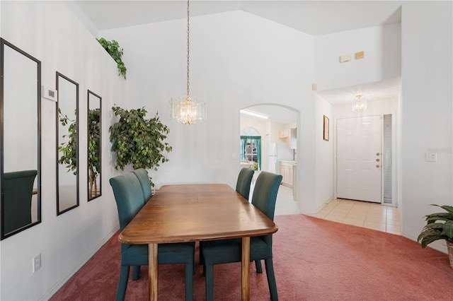 dining area with light tile patterned floors, high vaulted ceiling, and an inviting chandelier