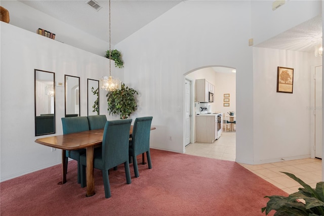 dining area featuring high vaulted ceiling, a notable chandelier, and light tile patterned flooring