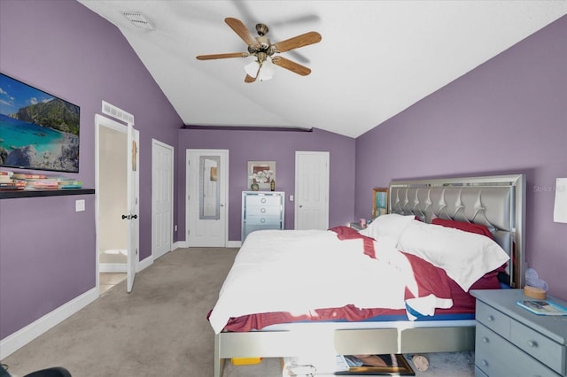 bedroom with ceiling fan, lofted ceiling, light carpet, and two closets