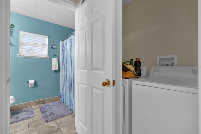 clothes washing area featuring light tile patterned flooring, washer and dryer, and a textured ceiling