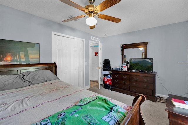 bedroom with ceiling fan, a closet, light carpet, and a textured ceiling