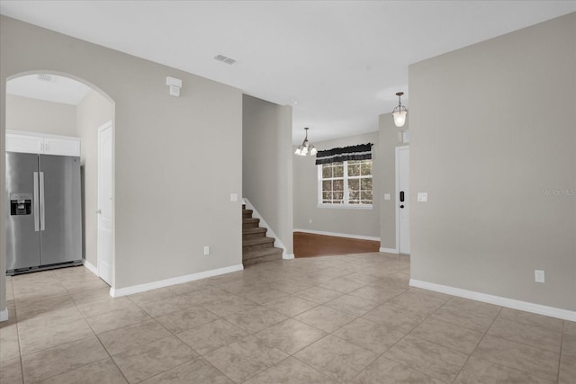 tiled spare room with a chandelier