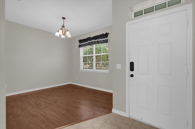 tiled entryway with baseboards and a notable chandelier