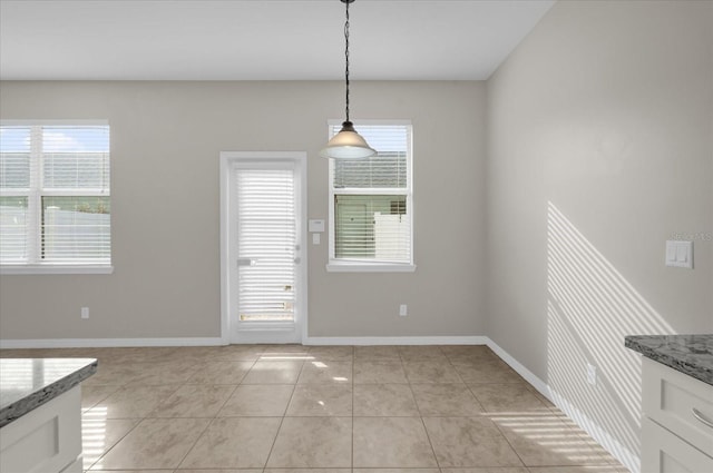 unfurnished dining area with light tile patterned floors and baseboards