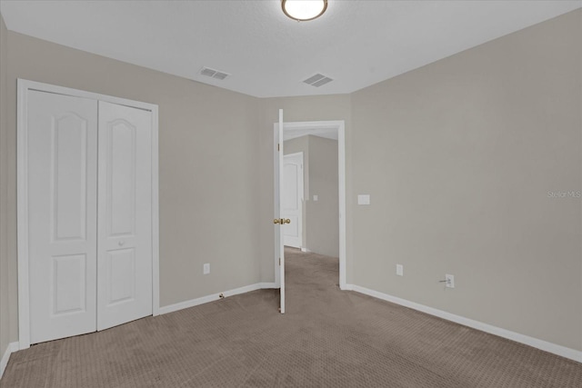 unfurnished bedroom with a closet, visible vents, baseboards, and carpet