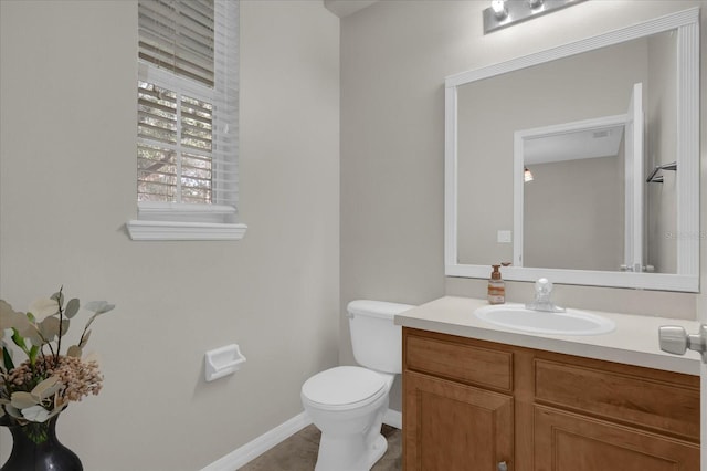 half bathroom with tile patterned floors, toilet, vanity, and baseboards