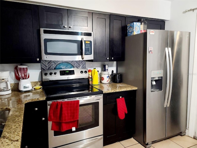 kitchen featuring appliances with stainless steel finishes, light stone counters, and light tile patterned flooring