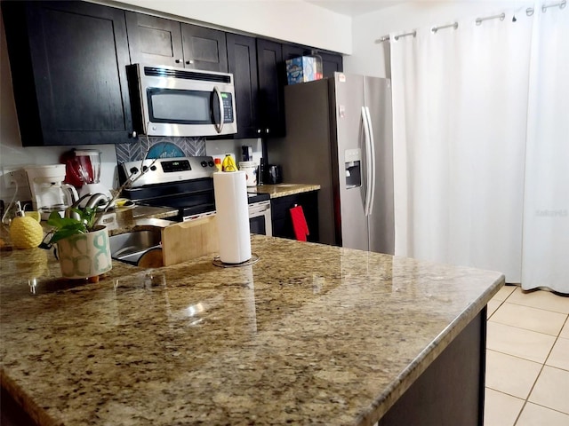 kitchen with light stone countertops, light tile patterned floors, and stainless steel appliances