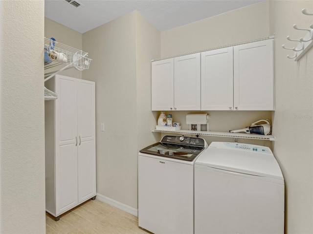 laundry room featuring separate washer and dryer and cabinets