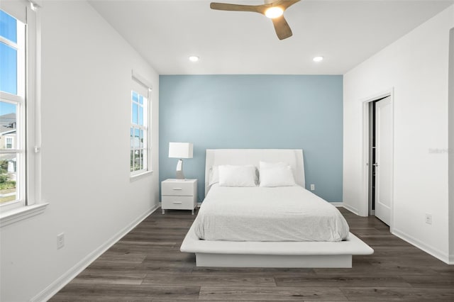 bedroom featuring ceiling fan, dark hardwood / wood-style flooring, and multiple windows