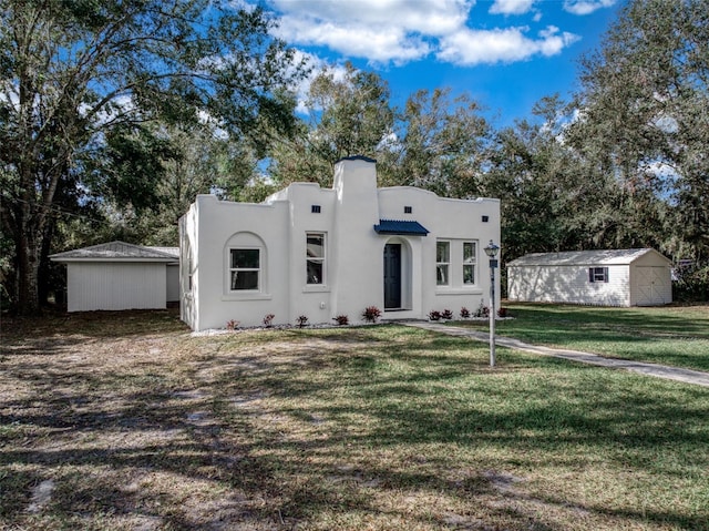 pueblo revival-style home featuring a shed and a front lawn