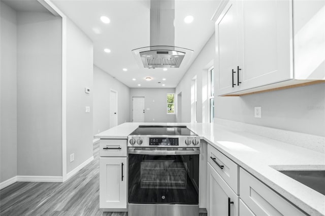 kitchen featuring stainless steel electric stove, white cabinets, and island exhaust hood