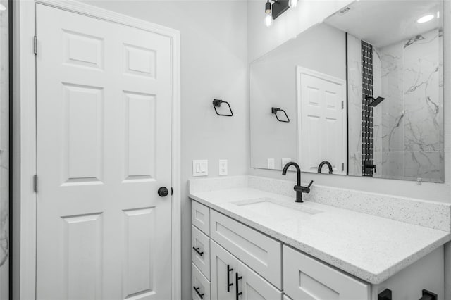 bathroom featuring tiled shower and vanity