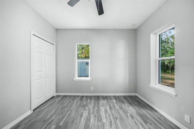 unfurnished bedroom featuring ceiling fan, multiple windows, and a closet