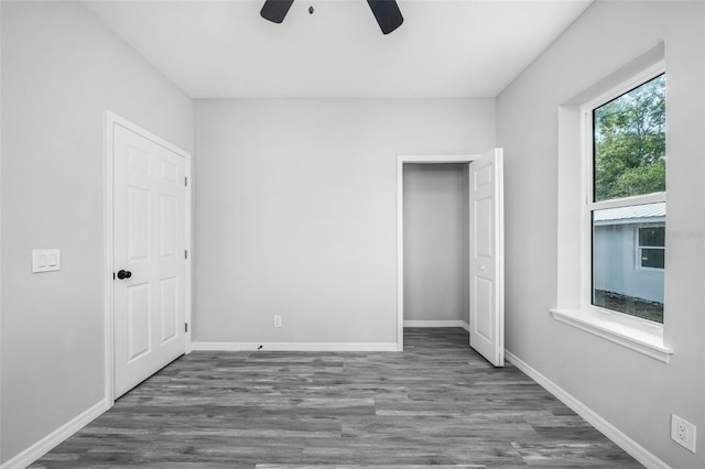 unfurnished bedroom featuring multiple windows, dark hardwood / wood-style flooring, and ceiling fan