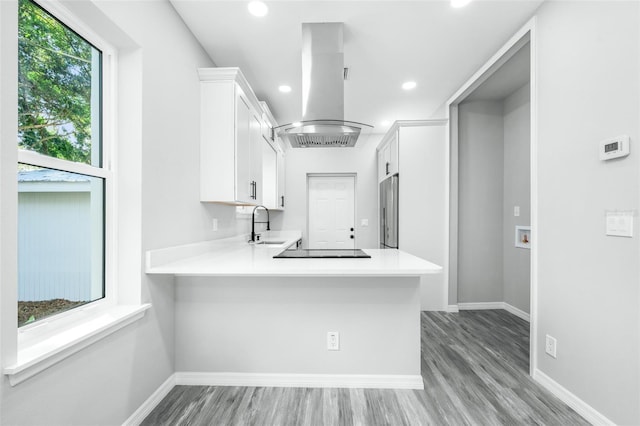 kitchen with white cabinets, island range hood, and kitchen peninsula