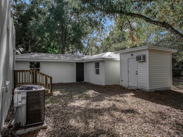 rear view of house featuring a wall mounted AC and central AC unit