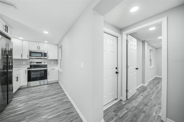 kitchen with white cabinets, appliances with stainless steel finishes, and light hardwood / wood-style flooring