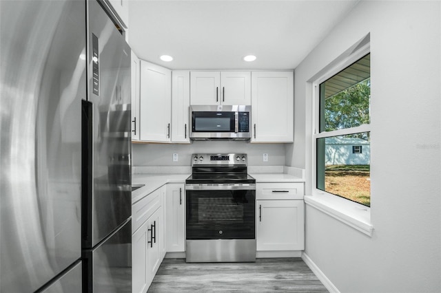 kitchen featuring white cabinets, light wood-type flooring, and appliances with stainless steel finishes