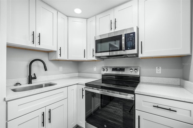 kitchen with light stone counters, sink, white cabinets, and stainless steel appliances