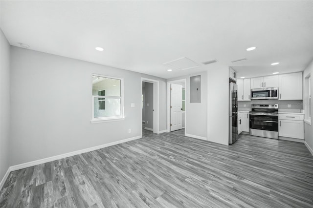 kitchen with white cabinets, electric panel, appliances with stainless steel finishes, and light hardwood / wood-style flooring