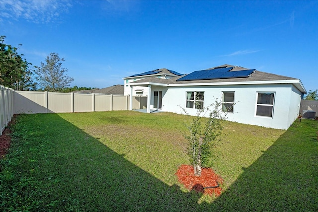 back of property featuring solar panels, a yard, and central air condition unit