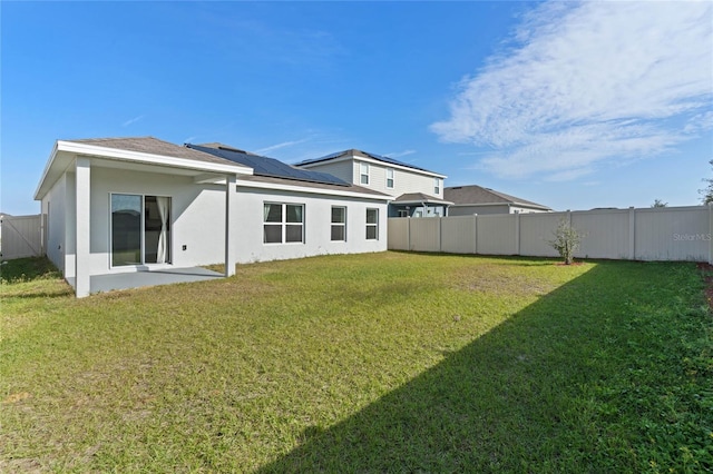 back of property featuring solar panels, a patio area, and a lawn