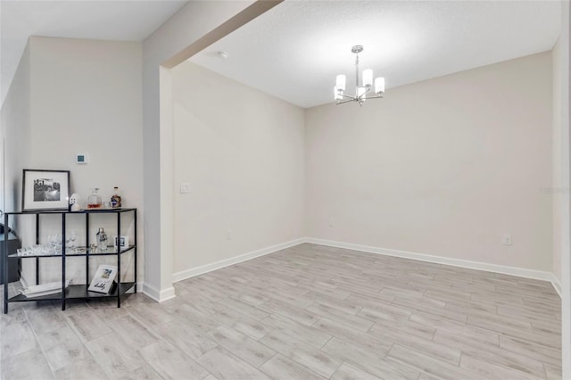 empty room featuring light hardwood / wood-style floors and a notable chandelier