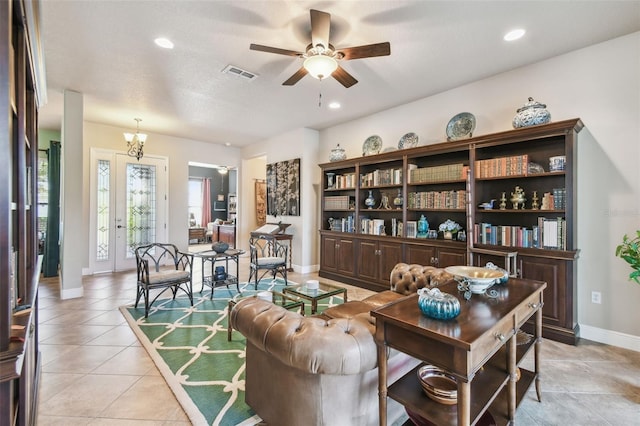 living area featuring a textured ceiling, ceiling fan with notable chandelier, and light tile patterned floors