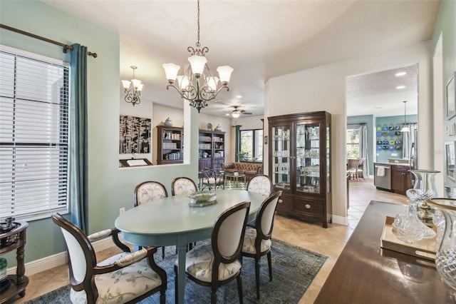 tiled dining area featuring ceiling fan with notable chandelier and a healthy amount of sunlight