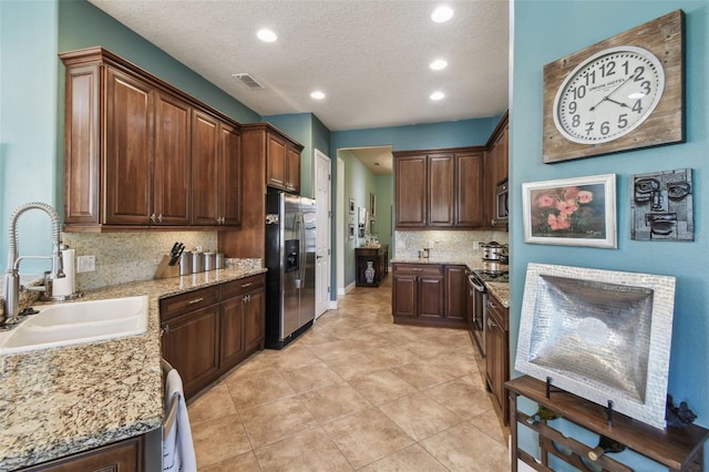 kitchen with light stone countertops, sink, backsplash, a textured ceiling, and appliances with stainless steel finishes