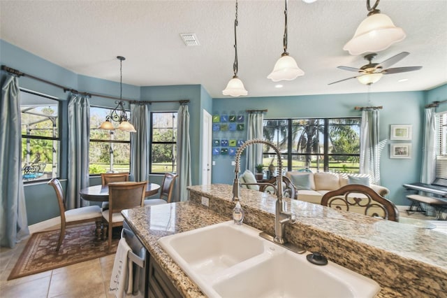 kitchen with sink, light tile patterned floors, stainless steel dishwasher, and a textured ceiling